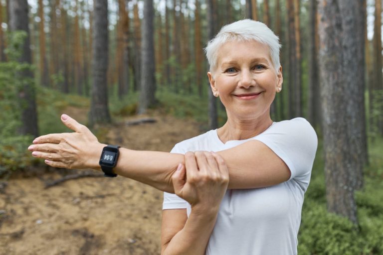 Arthrose de l'épaule, une dame étire son épaule dans la forêt