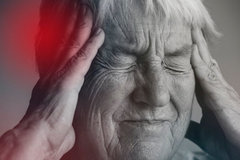 vieille dame qui se tient la tête dans les mains qui a une migraine
